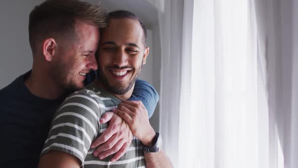 Multi ethnic gay male couple embracing and smiling