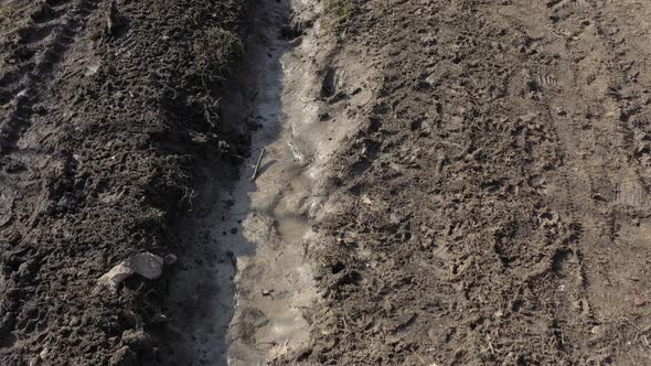 Muddy road puddle with vehicle tires marks 4K drone video