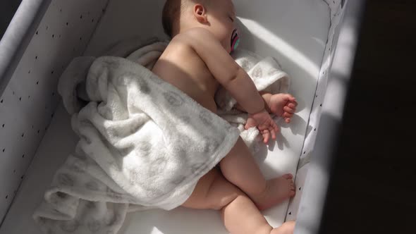 Top View Face of Newborn Nnaked Sleeping Little Small Infant Baby Boy Lying On Side On Soft White