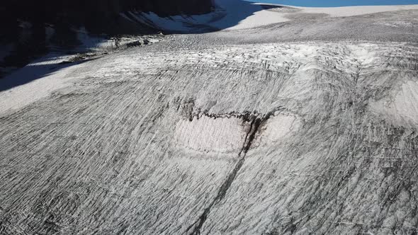 Tilt up drone view of a glacier with crevices in the swiss alps, rocky mountains.