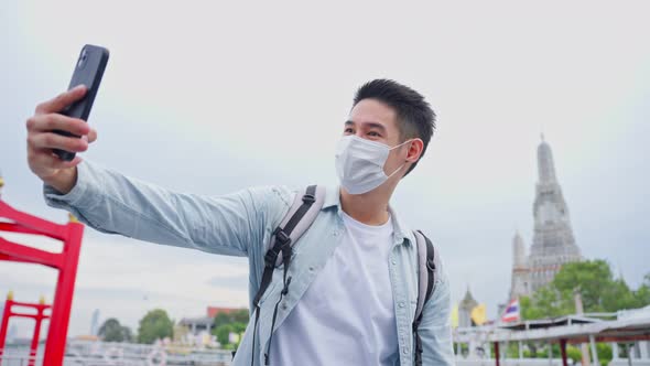 Asian young male backpacker use smartphone selfie take picture in city.