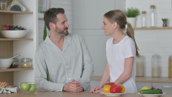 Happy Young Couple Talking While Standing in Kitchen