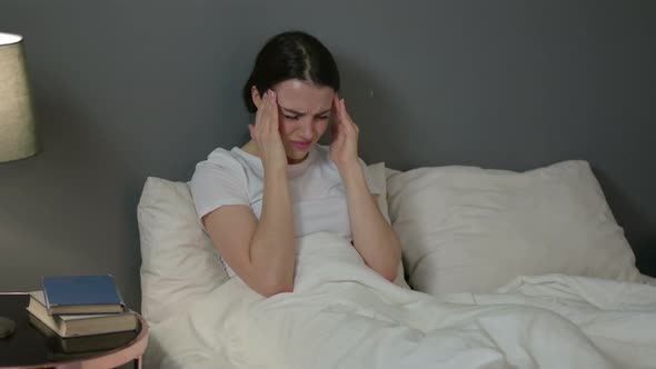 Young Woman with Headache Sitting in Bed 