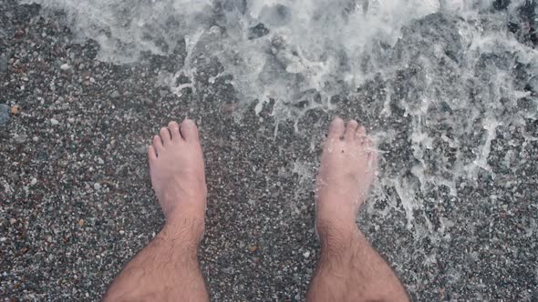 Men's feet cooling on waves of sea