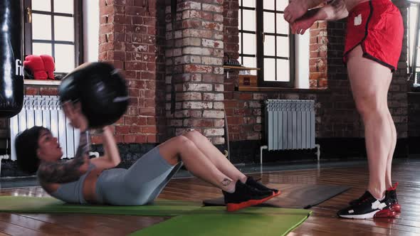 A Couple Training in the Gym  Tattooed Woman Pumping Her Abs and Holding the Ball