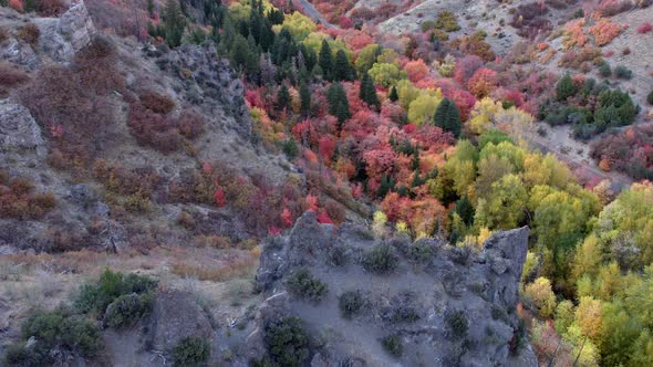 Flying past rocky hilltop viewing Fall colors in canyon