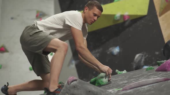 Professional Climber Training on a Climbing Wall Practicing Rockclimbing and Makes a Jump Vertical