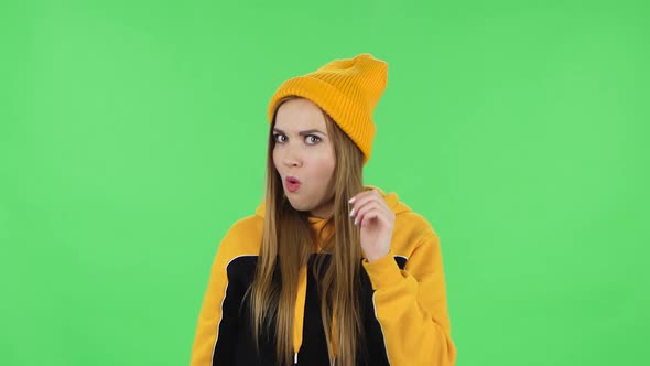 Portrait of Modern Girl in Yellow Hat Is Holding Hand Near Ear Trying To Listen To Interesting News