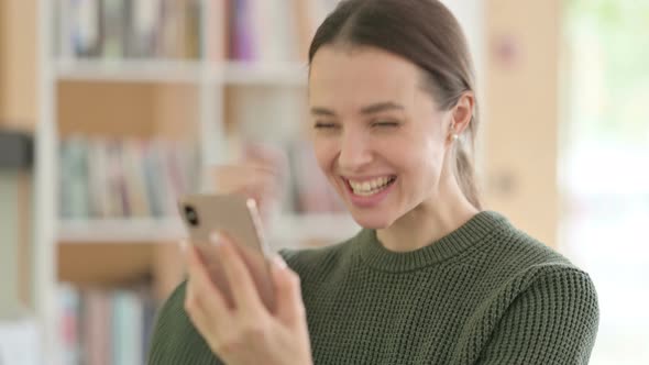 Young Woman Celebrating Online Success on Smartphone 