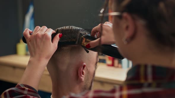 Barbershop: woman hairdresser cuts man's hair with a razor