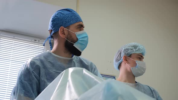 Surgeon with Assistant Doing Operation in Clinic