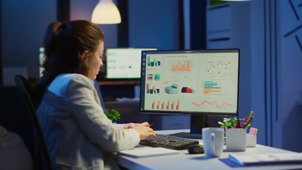 Busy Woman Working at Night in Front of Computer Taking Notes