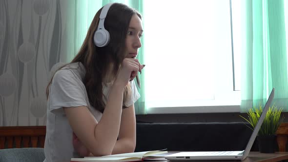 Girl Student Wearing Headphones Studying Online with Internet Teacher Looking at Laptop