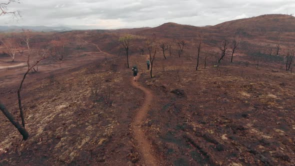 Aerial drone shot following hikers in scorched landscape, Central Australia