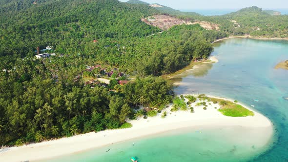 Holiday resort with bungalows inside tropical trees forest, white sandy beach washed by calm clear w