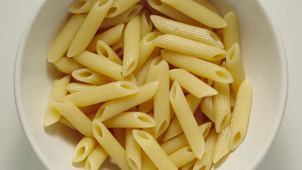 Ribbed Penne Pasta Falling Into A White Plate