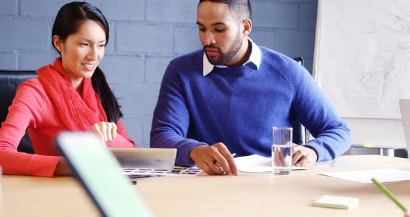 Male and female business executives discussing over a digital tablet