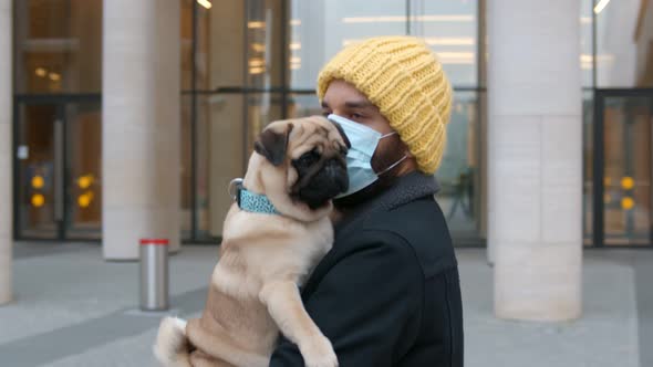 Man in Face Mask Walking with Dog During Coronavirus in City Center