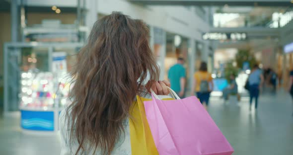 A Girl is Walking Through a Shopping Center with Bags on Her Shoulder