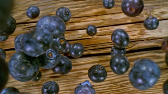 Super Slow Motion Detail Shot of Fresh Blueberries Falling on Wooden Table at 1000Fps