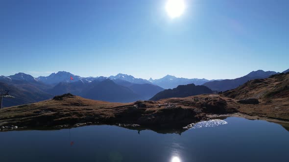 Solo hiker walks around an idyllic lake in beautiful Switzerland, aerial orbit