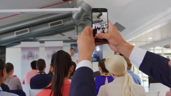 Man in audience at a business conference filming with smartphone