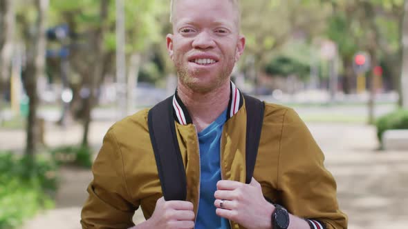 Portrait of smiling albino african american man with dreadlocks in park looking at camera