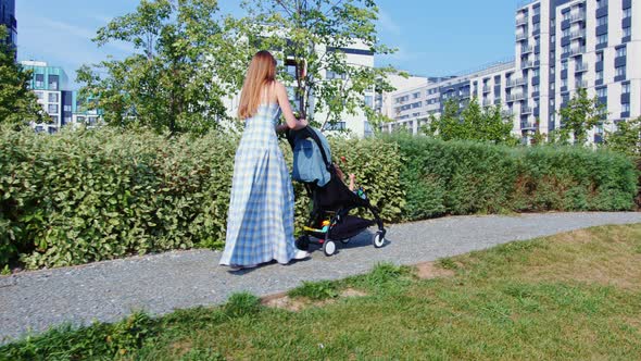 Lady in Sundress Pushing Baby Stroller with Boy or Girl