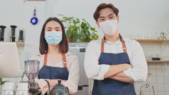 Portrait of young attractive Asian waiter and waitress wearing protective mask due to Covid-19.