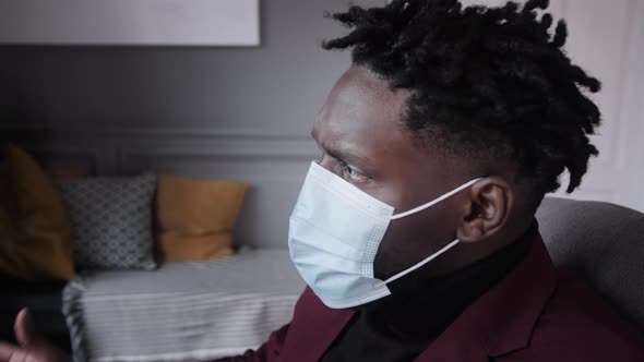 Black Business Man Works Behind a Laptop in a Protective Mask