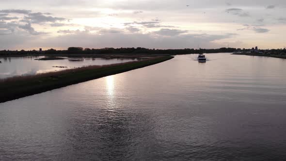 Inland Barge Travelling Across The River During Sunset In Netherlands. - aerial