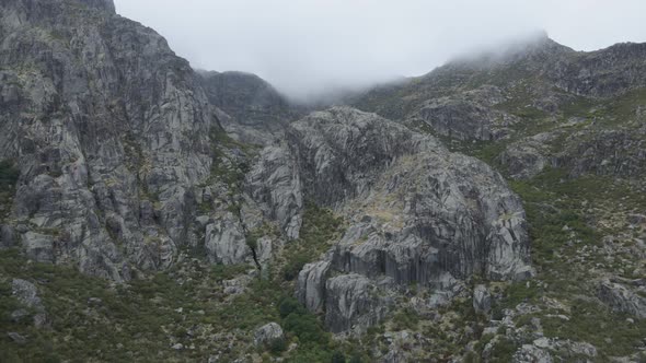 Rocky mountain shrouded in clouds, Covao da Ametade in Serra da Estrela, Portugal. Aerial drone view