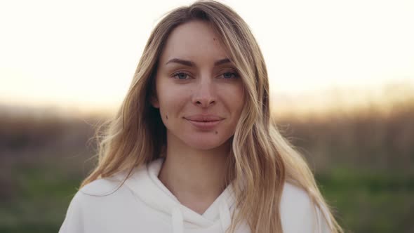 Natural Blonde Woman Look at Camera Outdoors with Blurred Background