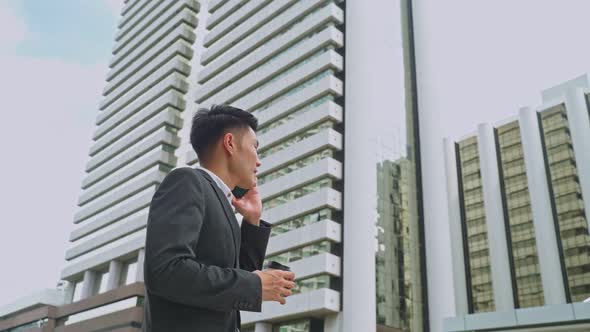 Asian young smart business man feel happy to walk outdoor to work and talking in telephone in city.