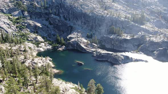 4K aerial cinematic drone footage showing a beautiful alpine lake with islands and waterfalls in Des