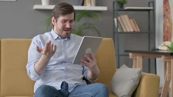 Young Man Having Loss on Tablet on Sofa