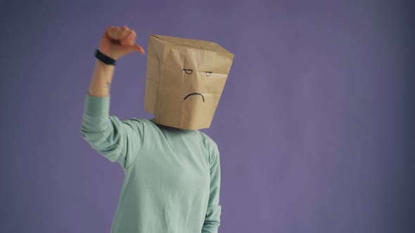 Portrait of Displeased Person with Paper Bag on Head Showing Thumbs-down Gesture