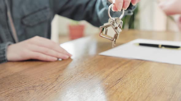 Close up of female client's hands signs the contract and receives the keys from the lawyer