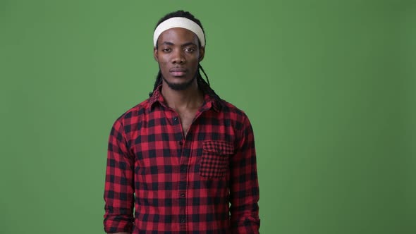 Young Handsome African Man with Dreadlocks Against Green Background