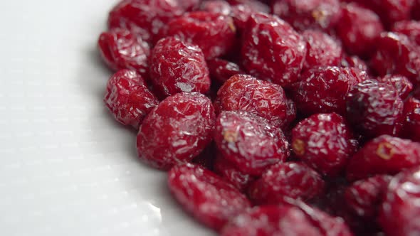 Dried red cranberries. Dry berries on white plate close up. Macro