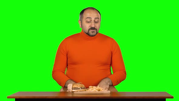 Man with Overweight Looks at Delicious Junk Foods on the Table and Wants To Eat It, Green Screen