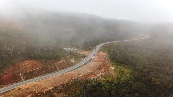 Winding Mountain Road near Misty Rainforest Trees, Drone View.