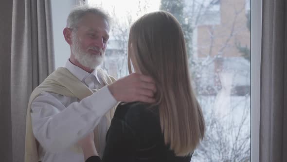 Portrait of Happy Wealthy Senior Man Hugging Young Brunette Woman Indoors. Handsome Middle-aged