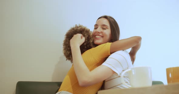 Two Multiethnic Friends Hug Each Other in a Coffee Shop