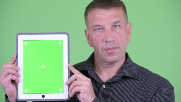 Face of Macho Mature Businessman Showing Digital Tablet