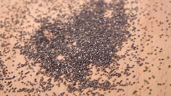 Falling chia seeds on a wooden cutting board