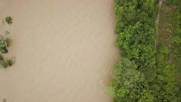 Aerial view of wide dirty river with muddy water in flooding period during heavy rains in spring.