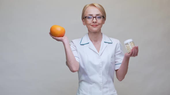 Nutritionist Doctor Healthy Lifestyle Concept - Holding Organic Grapefruit and Jar of Vitamin Pills