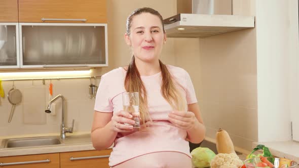 Portrait of Beautiful Smiling Pregnant Woman Drinking Vitamins in Pills with Clear Water