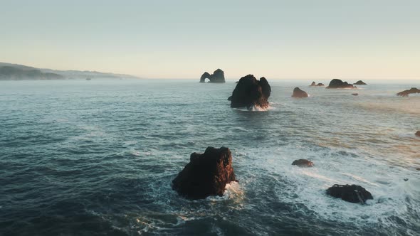 Drone Flying Fast Between Scenic High Sharp Dark Sea Rocks Aerial View Sunset